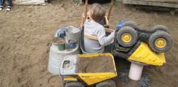 Child in poop machine in outdoor sandbox