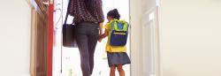 Parent holding daughters hand and walking through the door.