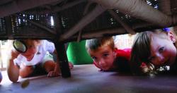 Children searching with magnifying glass under furniture. 