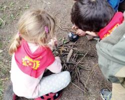 One child watches as another child pretends to build a fire.