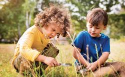 Children looking through magnetic glass in a field