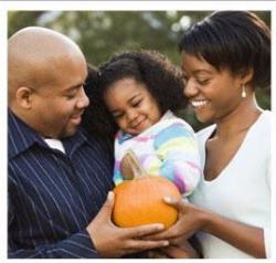 father, mother, and daughter holding a pumpkin