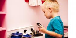 young boy playing with a kitchen playset in classroom