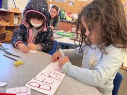 Children making signs in a classroom.