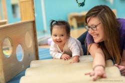 A teacher helping a toddler learn to crawl