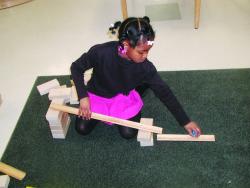 Young girl uses blocks to bulild