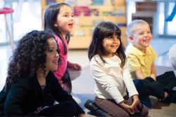 Four preschool students sitting on floor