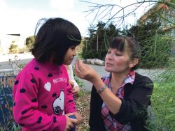 Teacher holding plant up to student's nose