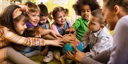 Diverse group of preschoolers with their hands on a globe