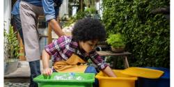 A young child sorting recycling into buckets.