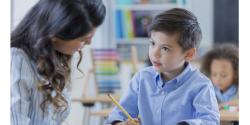 A child writing with a teacher.