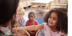 A child reaching towards a teacher.