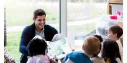 A teacher showing a picture book to children.