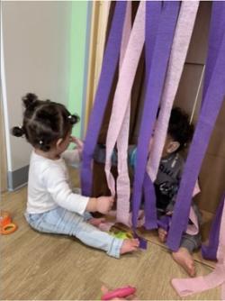 A toddler playing with streamers.