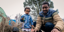 A father plays with his child outside.