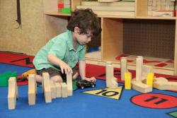 Preschool boy playing with blocks and a toy car on the floor 