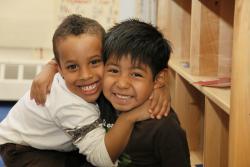 Two young boys hugging in a classroom