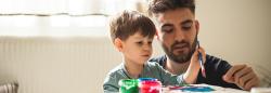 Young adult male painting with a preschool boy