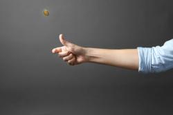 Person's hand flipping a coin