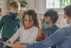 children and a teacher learning together while wearing protective masks