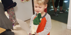 A child holds a sail car created from open-ended materials.