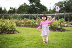 Child playing with a pinwheel in a garden