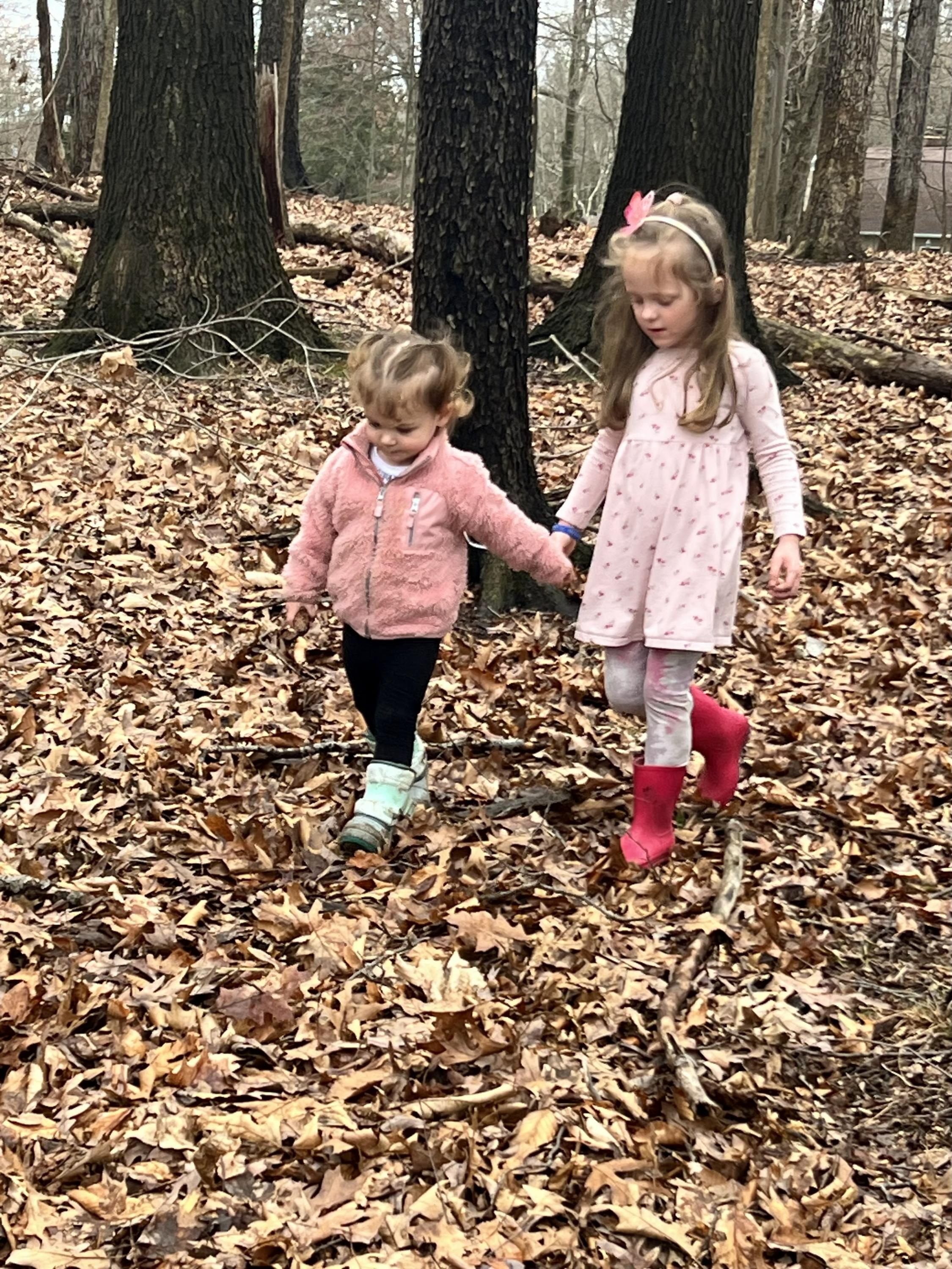 Two students holding hands while playing in the woods