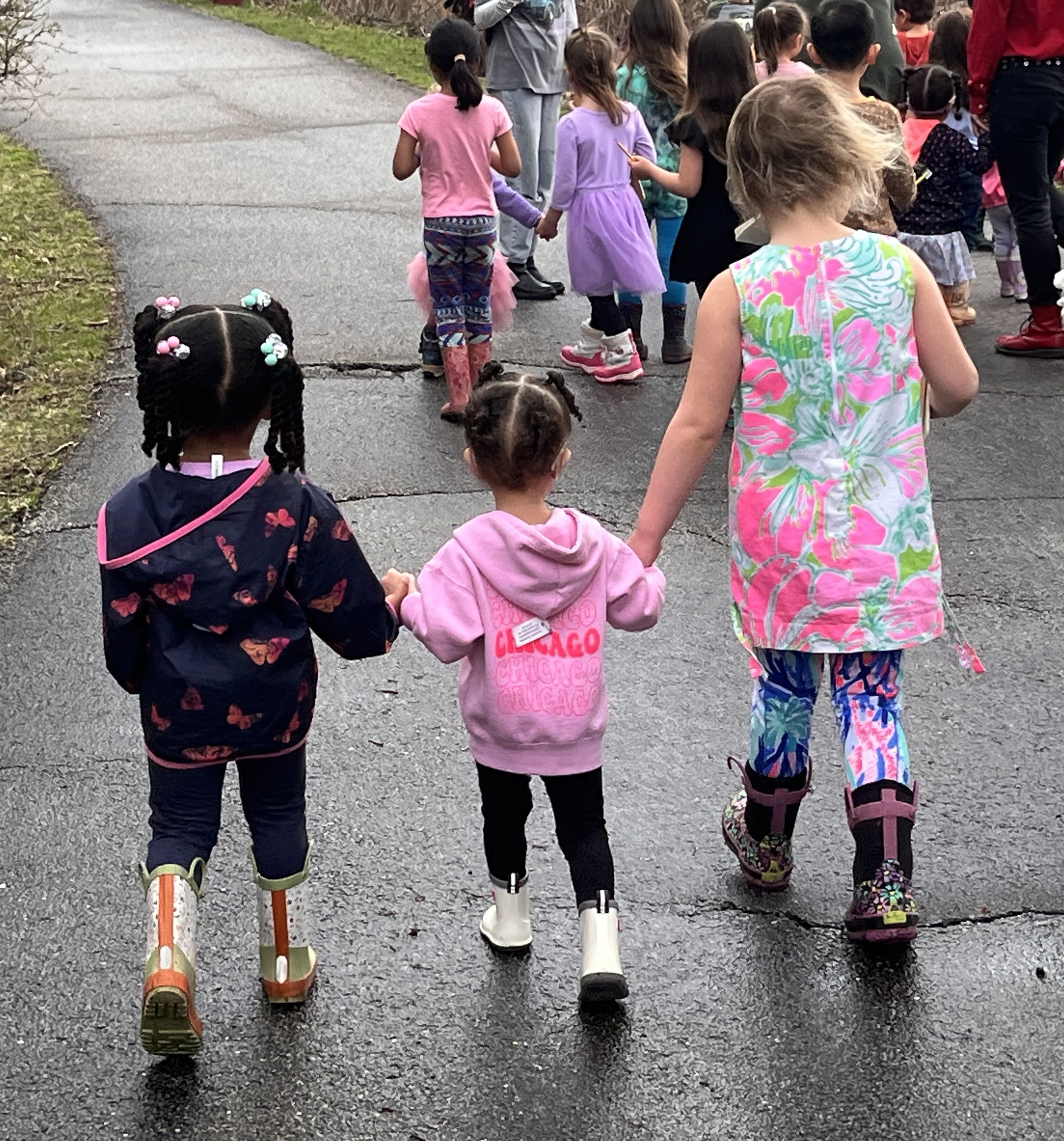 Three students holding hands while walking outside