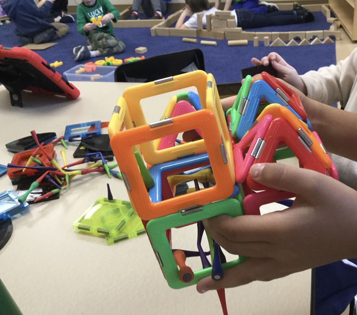 A child playing with magna tiles in a classroom