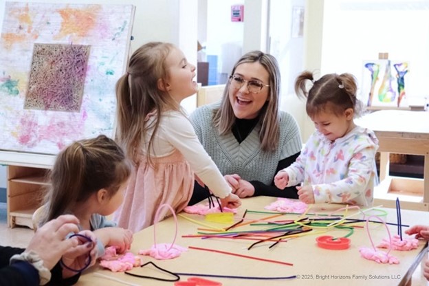 A teacher laughing with students in a classroom